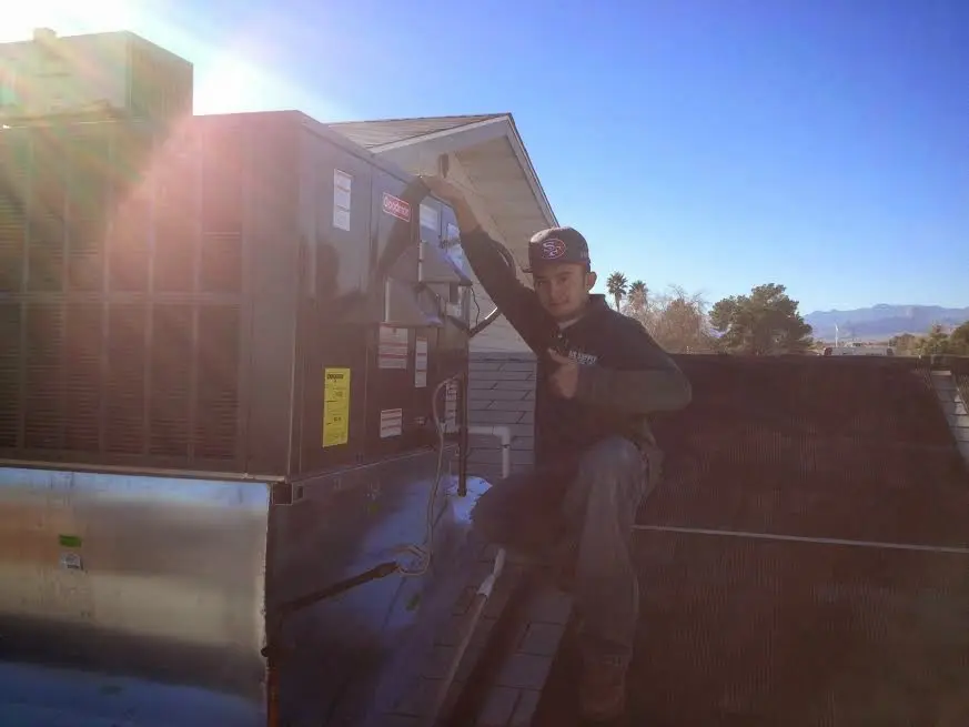 HVAC technician performing HVAC Inspection on a rooftop unit in Brighton